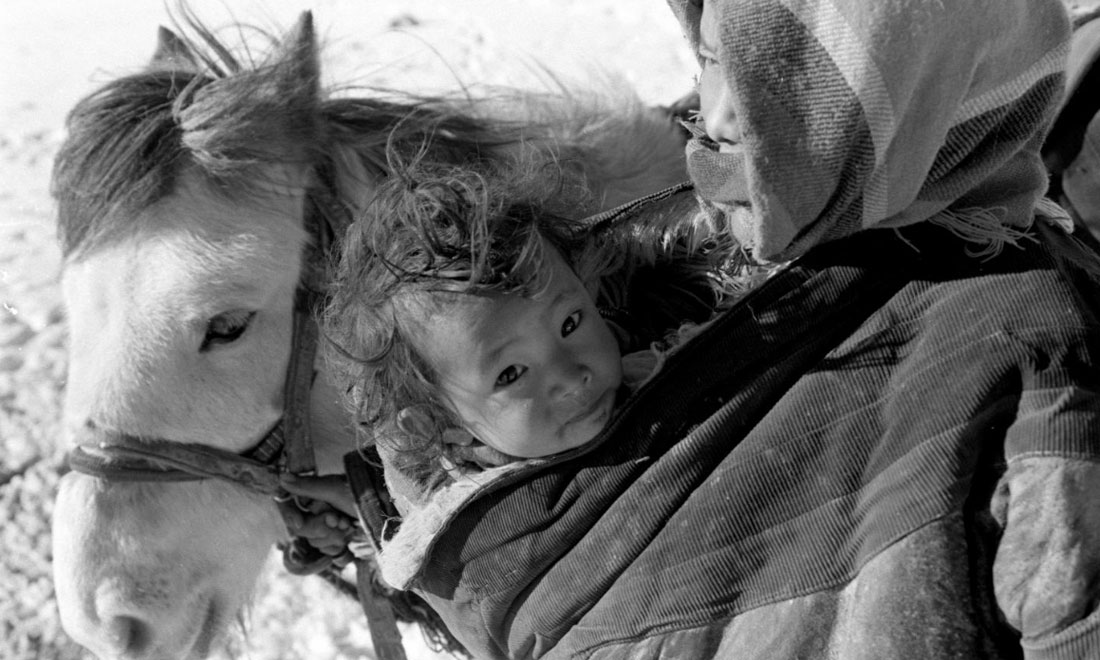 1990年3月，西藏當雄縣納木湖鄉三村女牧民斯卓不畏嚴寒，懷抱幼子，準備到遠處放牧。新華社記者覺果攝